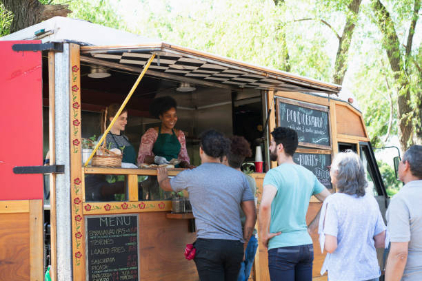 persone che fanno linea per acquistare cibo da camion di cibo - food truck foto e immagini stock