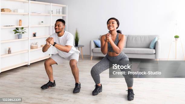 Strength Workout Concept Fit Black Woman And Her Boyfriend Doing Squats Together At Home Panorama Stock Photo - Download Image Now