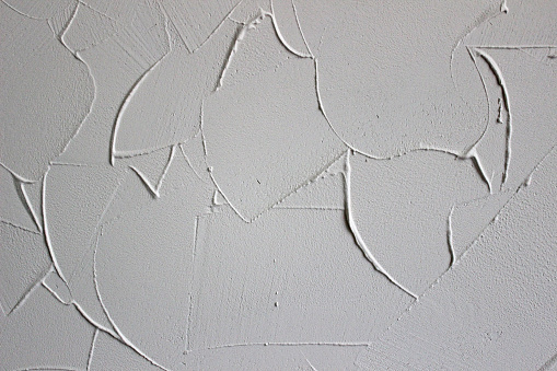 white textured background of filler paste applied with putty knife in irregular dashes and strokes