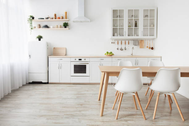 istock Scandinavian home interior. White kitchen furniture with utensils and dinner table with chairs, empty space 1322852883