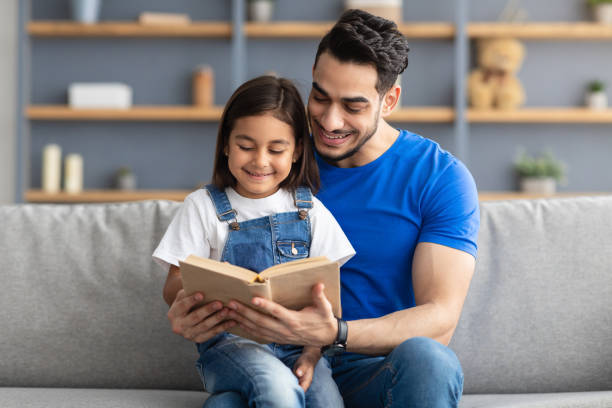 istock Father and daughter reading book spending time together at home 1322854221