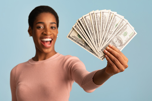 Big Prize. Happy Young African American Woman Demonstrating Dollar Cash Fan At Camera, Cheerful Excited Black Female Holding Lots Of Money, Standing Isolated Over Blue Background, Closeup Shot