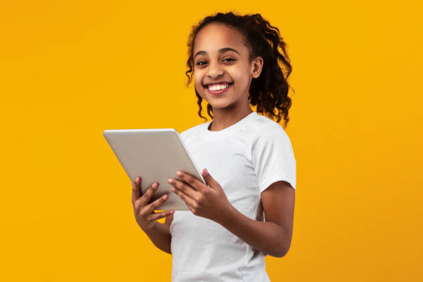 ragazza nera in piedi con tablet in studio giallo - schoolgirl school children isolated child foto e immagini stock