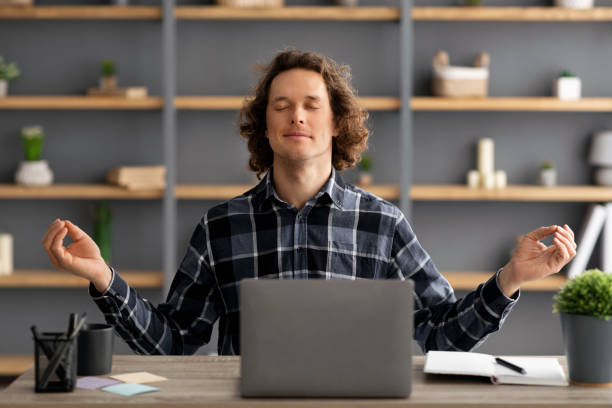 istock Young Businessman Meditating Sitting With Eyes Closed Relaxing At Workplace 1322855645