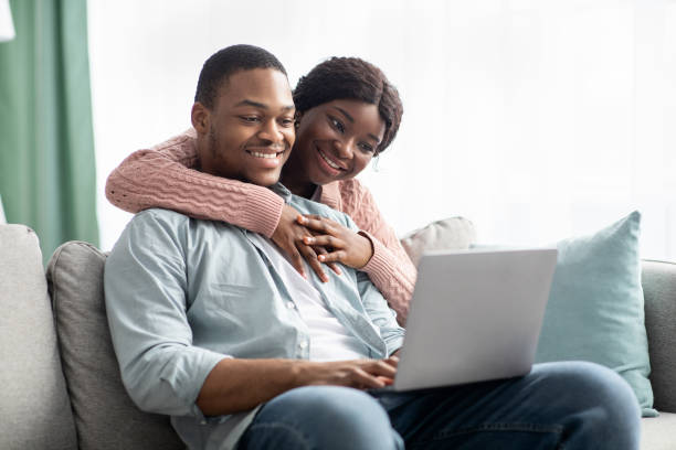 istock Cheerful african american family sitting on couch, using laptop 1322856322