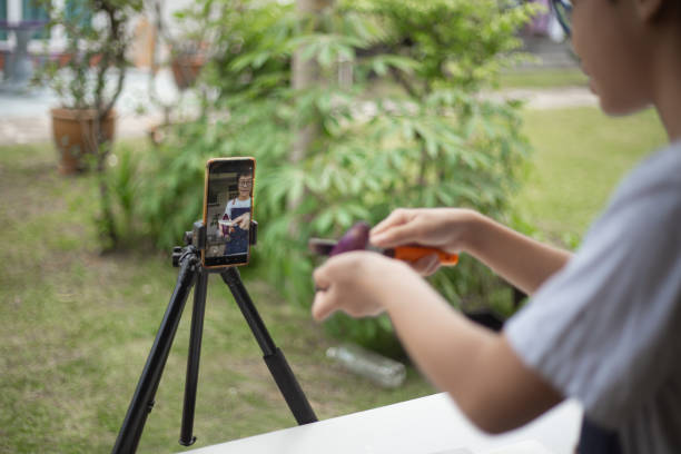 istock Asian Chinese teenager boy vlogging at backyard kitchen teaching cooking broadcasting. 1322858987