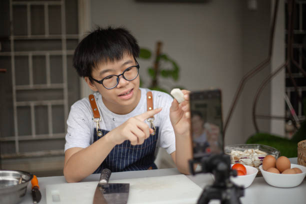 istock Asian Chinese teenager boy vlogging at backyard kitchen teaching cooking broadcasting. 1322858996