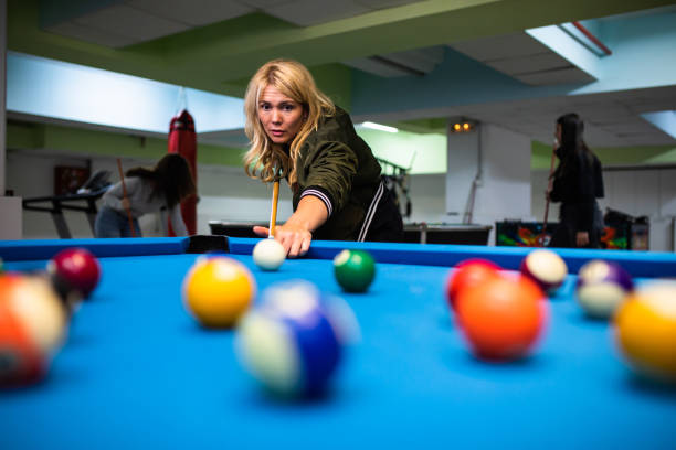 istock A young woman hitting a billiard ball with a cue 1322861744