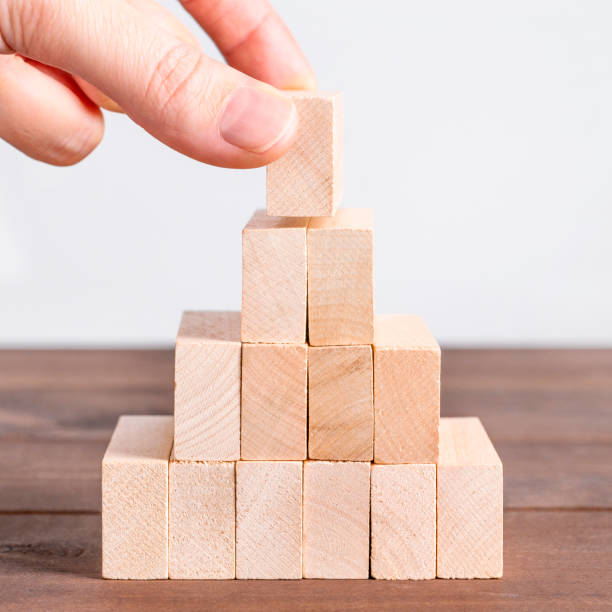 mujer haciendo pirámide con bloques de madera. concepto de negocio, jerarquía, éxito - block puzzle organization solution fotografías e imágenes de stock