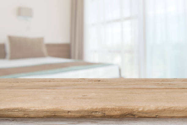 Wooden table top in front of defocused bedroom interior background