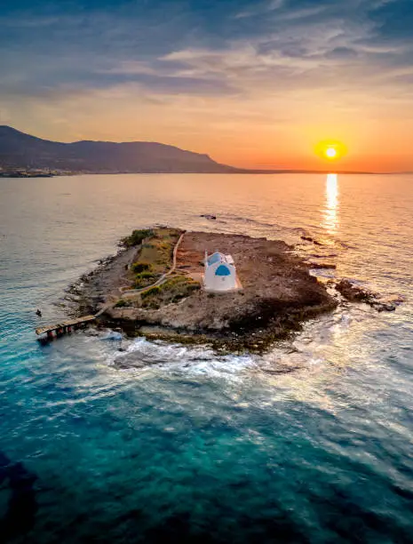 An old white church in a small island at sunset in Malia, Crete, Greece.