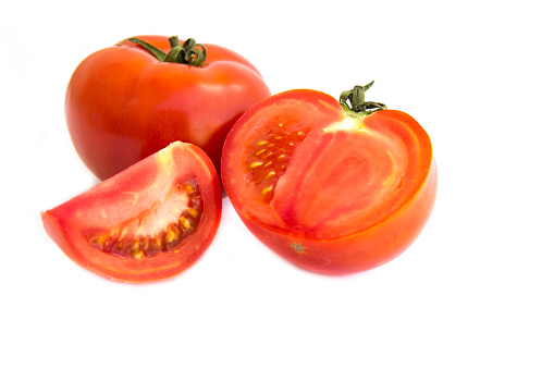 Group of ripe tomatoes with leaves isolated on white.