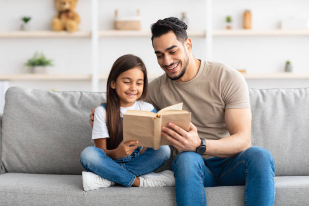 istock Father and daughter reading book spending time together at home 1322870540