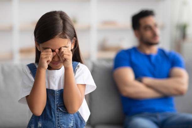 père assis séparé sur le canapé avec une petite fille offensée qui pleure - conflict face to face child arguing photos et images de collection