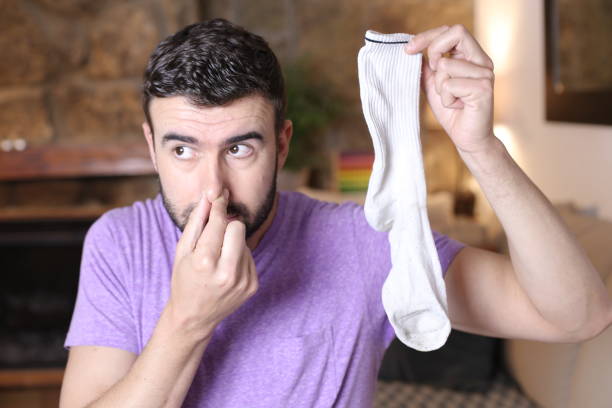 istock Funny guy smelling sock with fungus 1322873386