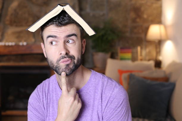 istock Pensive man with open book above head 1322873388