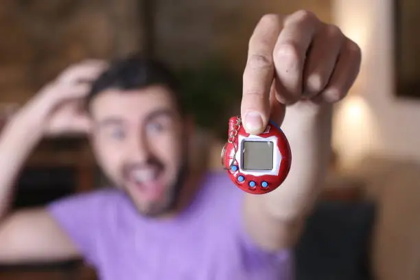 Photo of Millennial guy excited with his tamagochi