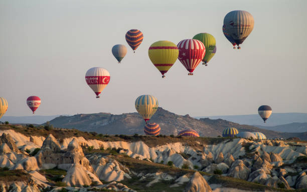 balões de ar quente voando sobre goreme com formações de arenito ao nascer do sol. - goreme rural scene sandstone color image - fotografias e filmes do acervo