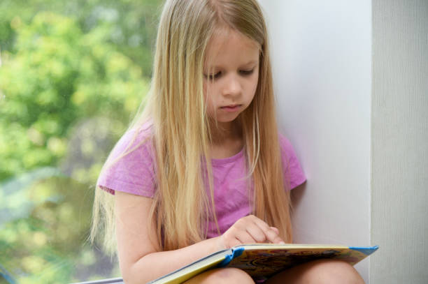istock Child reading a book in the afternoon at the window 1322876664