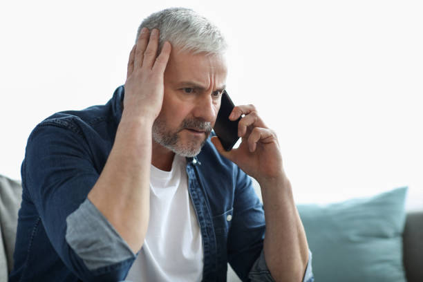 istock Worried elderly man having phone conversation, touching his head 1322877029
