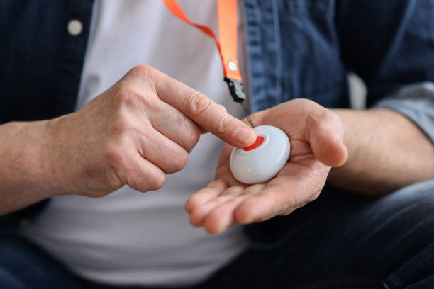 Hand pushing panic button on emergency equipment for elderly people