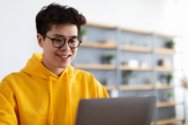 istock Smiling asian man working on laptop at home 1322877875