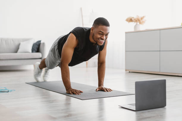 istock African Man Training At Laptop Standing In Plank At Home 1322878398