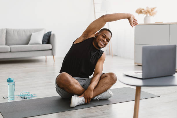 istock Happy Black Guy Doing Stretching At Laptop Exercising At Home 1322879341