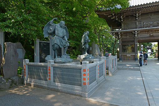 The statue of the Tengu placed at the entrance of Yakuou-in Temple and the scenery of tourists watching it, shooting record June 10, 2021, Hachioji City, Tokyo, Japan.