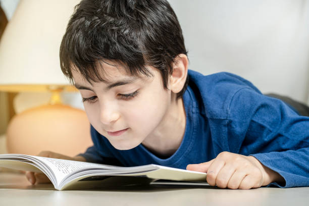 istock Cute little boy reading book under a tent at home alone 1322880087