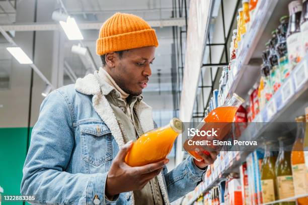 African Man Chooses Natural Juice In Glass Bottles In A Grocery Supermarket Stock Photo - Download Image Now