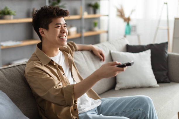 istock Happy asian guy spending weekend watching tv 1322885673