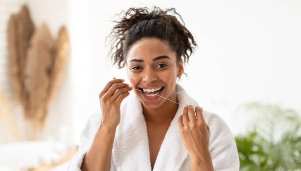 black lady flossing teeth enjoying oral hygiene routine in bathroom - dental floss brushing teeth dental hygiene dental equipment imagens e fotografias de stock