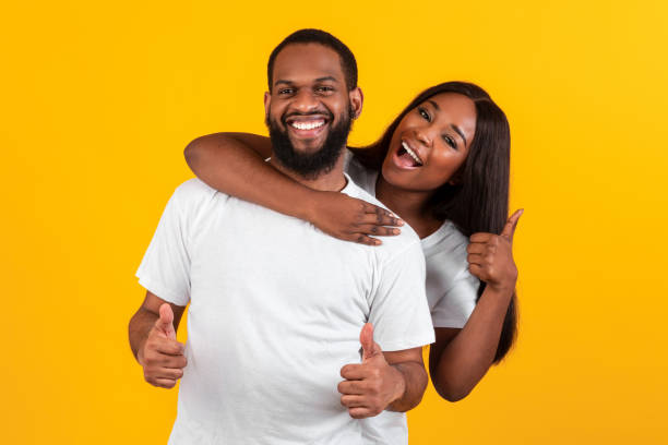 istock Happy afro couple gesturing thumbs up, hugging and smiling 1322886102