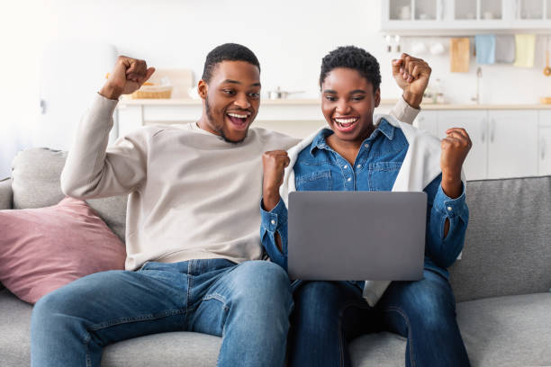 istock Afro couple using laptop celebrating success shaking fists 1322886255