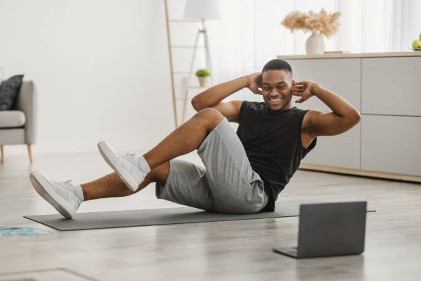 istock Happy Black Man Doing Elbow-To-Knee Abs Crunches At Laptop Indoor 1322886900