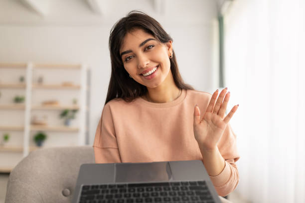 istock Woman having video call using laptop and waving 1322887050