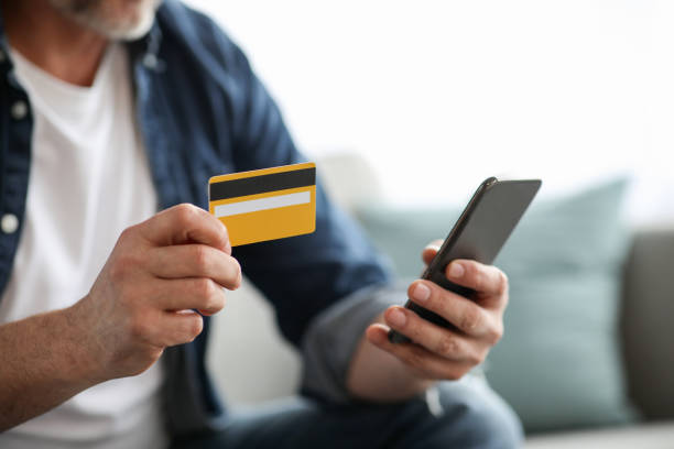 istock Unrecognizable man with smartphone holding credit card 1322887094