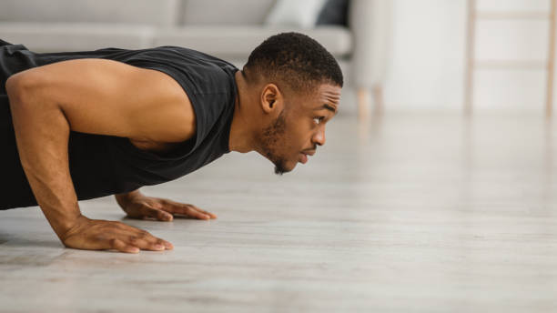 istock Athletic Black Guy Doing Push-Ups Exercising On Floor At Home 1322887281