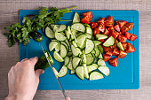 Top view of a woman cooking healthy food. Slicing vegetables