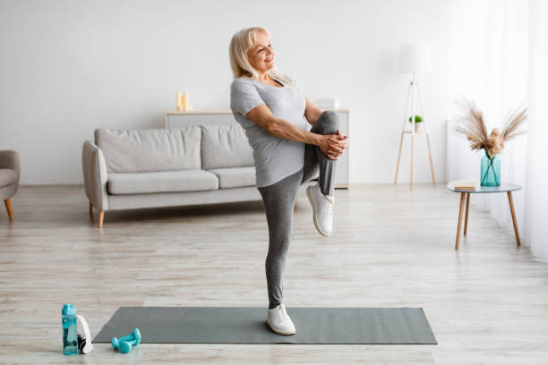 istock Mature woman exercising at home stretching leg 1322887372