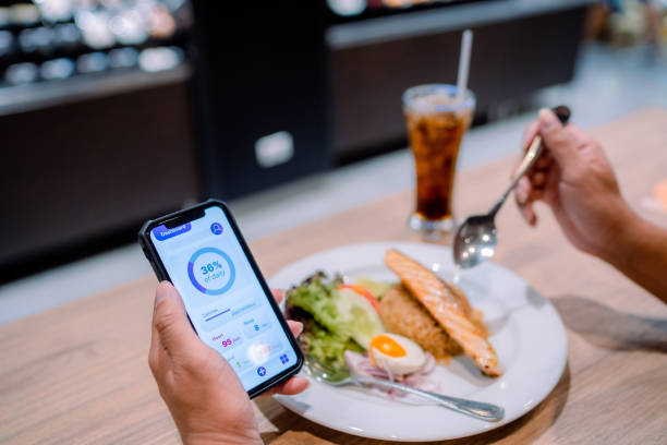 istock Asian man checking his daily calculations and calories while having lunch. 1322887998