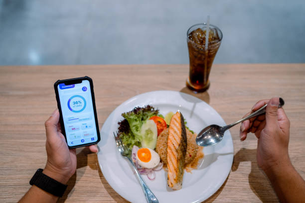 istock Asian man checking his daily calculations and calories while having lunch. 1322888013