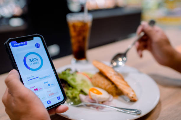 istock Asian man checking his daily calculations and calories while having lunch. 1322888025