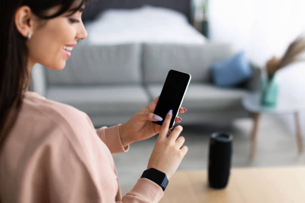 istock Back view of woman using phone with empty mockup screen 1322888696