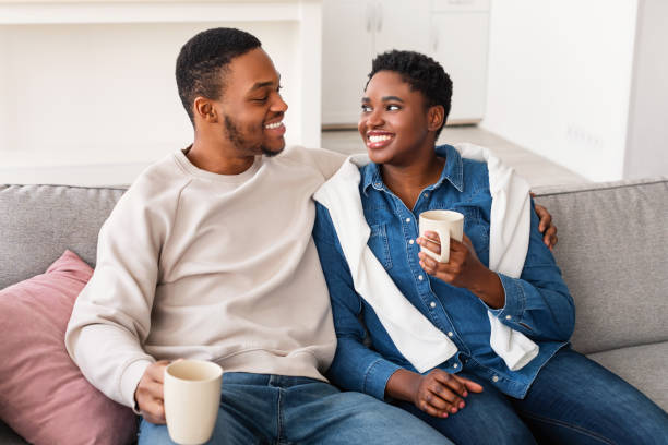 istock Black couple drinking coffee spending time together resting on couch 1322888824