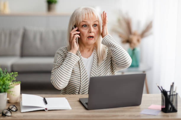 surprised shocked mature woman talking on mobile phone - ongebruikelijk stockfoto's en -beelden