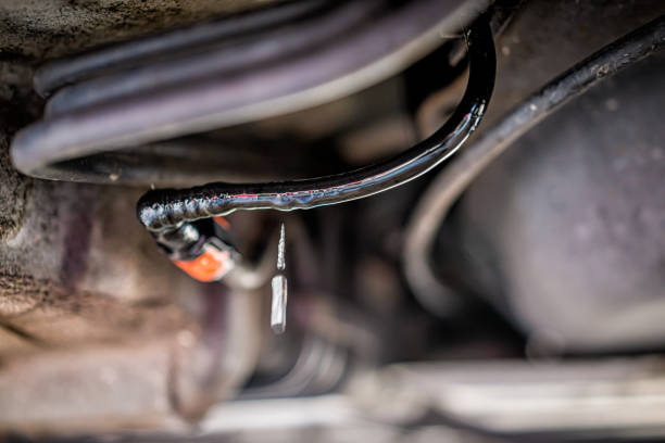 macro primer plano larga exposición de vehículo con fugas de líquido combustible debajo del coche con textura de cables húmedos y caída de gota. los cables fueron masticados por roedores causando el peligro. - cable car fotos fotografías e imágenes de stock