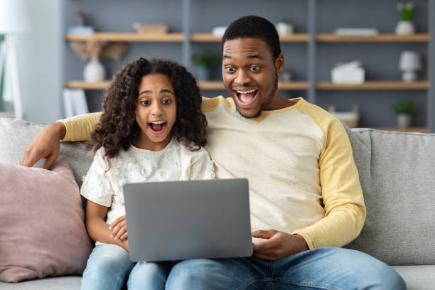istock Shocked black dad and daughter using computer at home 1322891285