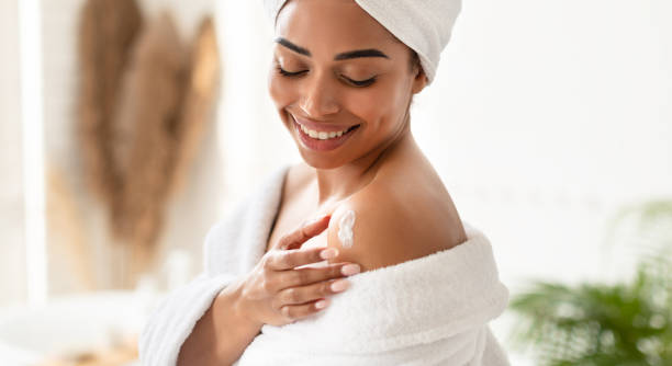 istock Black Young Woman Applying Moisturizer Cream On Shoulders In Bathroom 1322892008